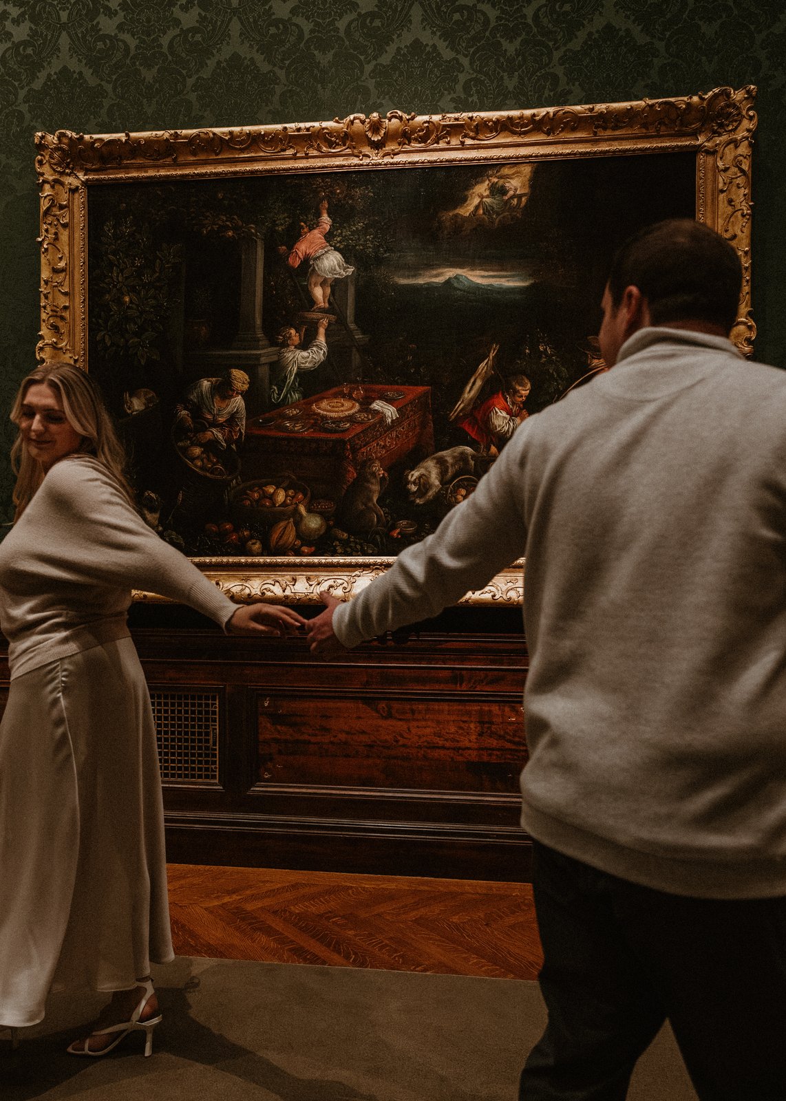 Karley and Michael holding hands in front of a gilded painting
